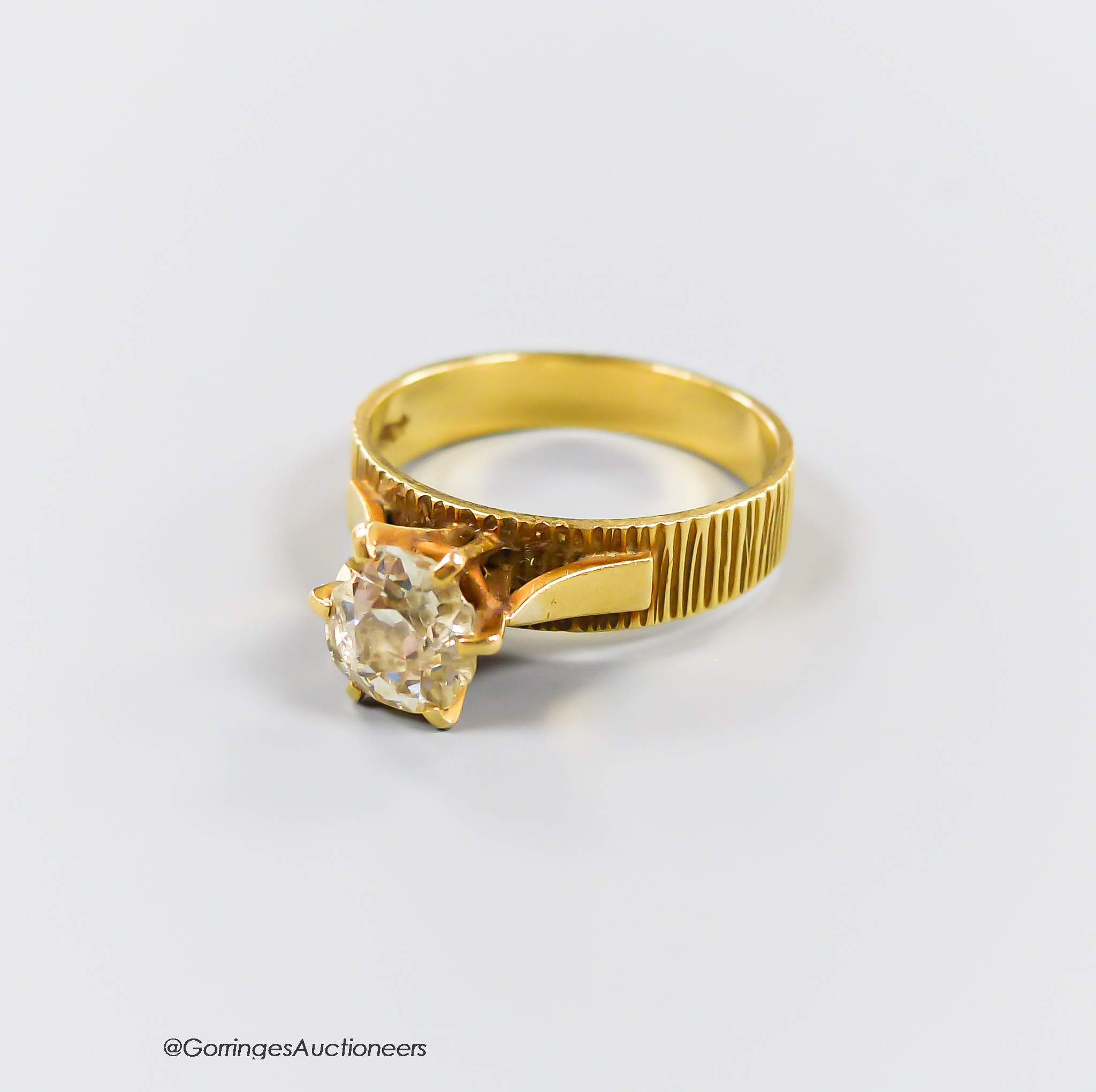 A textured 18ct and solitaire diamond ring, size Q, gross weight 5.4 grams, the stone diameter 7.5mm, (chipped).